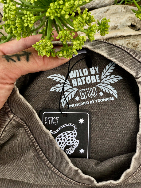 Close-up of the inner neck print and tag of the Lost in the Wild tee, with the text “Wild by Nature” and TDONAIRE branding