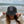 Woman wearing the Stay Wild bucket hat at the beach, holding the brim down over her face with ocean in the background