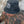 Man wearing the black Stay Wild bucket hat with white panther logo and “BCN XXV” text, sitting shirtless against a stone wall