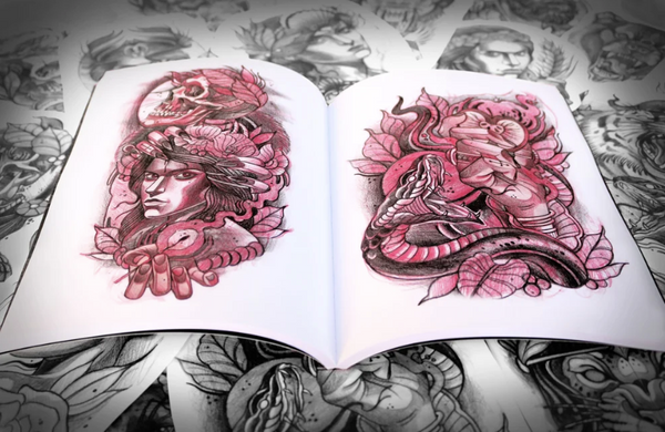 Open sketchbook displaying two full-color tattoo designs. On the left, a stylized portrait of a woman with feathers and a skull; on the right, a composition with a snake and dynamic feminine figure. Red pencil shading and black ink dominate both pieces.
