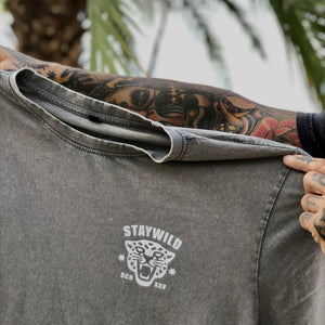 Arms holding Lost in the wild tee. Front side
