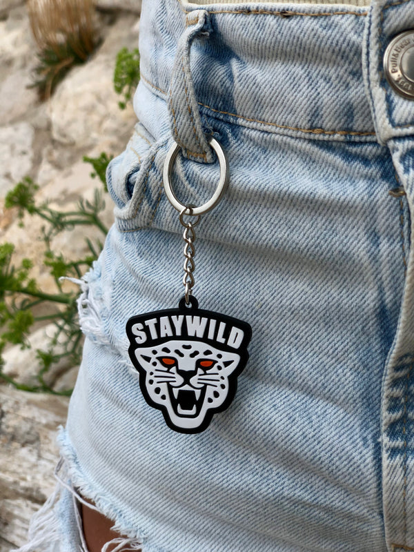llavero Stay Wild colgando en la hebilla de un pantalon